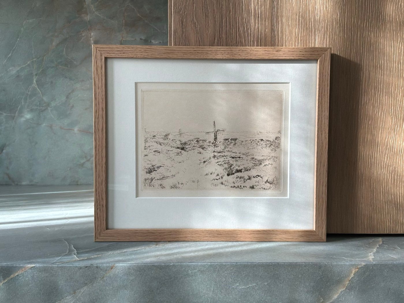 Ingelijste ets tegen een houten wand